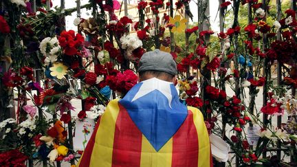 Un sympathisant de l'indépendance catalane dépose une fleur devant un bureau de vote utilisé lors du référendum d'autodétermination, mardi 3 octobre 2017 à Barcelone. (PAU BARRENA / AFP)