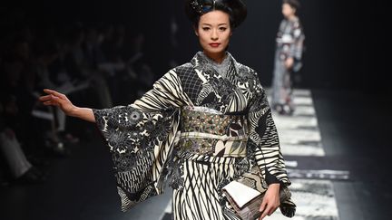 "Le kimono est mode, on ne doit pas le présenter comme dépassé", expliquait en 2015 à l'AFP Jotaro Saito . "Je veux faire passer un message, il peut se porter tous les jours, il peut se porter comme un vêtement moderne, pas comme si les gens mettaient un costume". Le couturier japonais est né à Kyoto au sein d'une famille qui teignait les kimonos et travaille avec ce vêtement depuis 20 ans. Pour lui, le changement est crucial si le kimono veut avoir un avenir dans la mode.
 (TORU YAMANAKA / AFP)