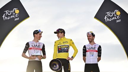 Le podium final du Tour de France 2023 avec Jonas Vingegaard (centre), Tadej Pogacar (gauche) et Adam Yates (droite), le 23 juillet 2023. (MARCO BERTORELLO / AFP)