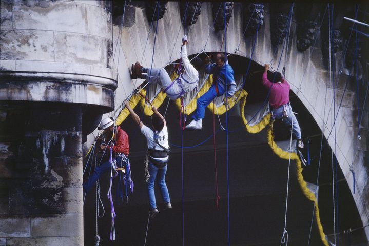 Des alpinistes attachent la toile hissée sous l'une des arches du Pont Neuf&nbsp; (© Christo 1985 Photo © Wolfang Volz)