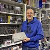 Cyril, devant sa collection de jeux et de consoles, qui tient un exemplaire de la première version de la PlayStation sortie au Japon, le 3 décembre 1994. (LOUIS MONDOT / FRANCEINFO / RADIO FRANCE)