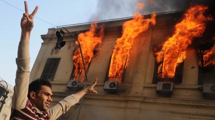 Un manifestant &eacute;gyptien devant un b&acirc;timent en feu au Caire (Egypte), le 17 d&eacute;cembre 2011. (MOHAMMED HOSSAM /&nbsp;AFP PHOTO)