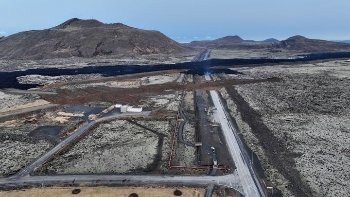 La barrière érigée ces dernières semaines au nord de Grindavik, afin de prévenir une éventuelle éruption. La route a été bouchée au dernier moment, dimanche matin, et un léger déversement y est observé. (HALLDOR KOLBEINS / AFP)