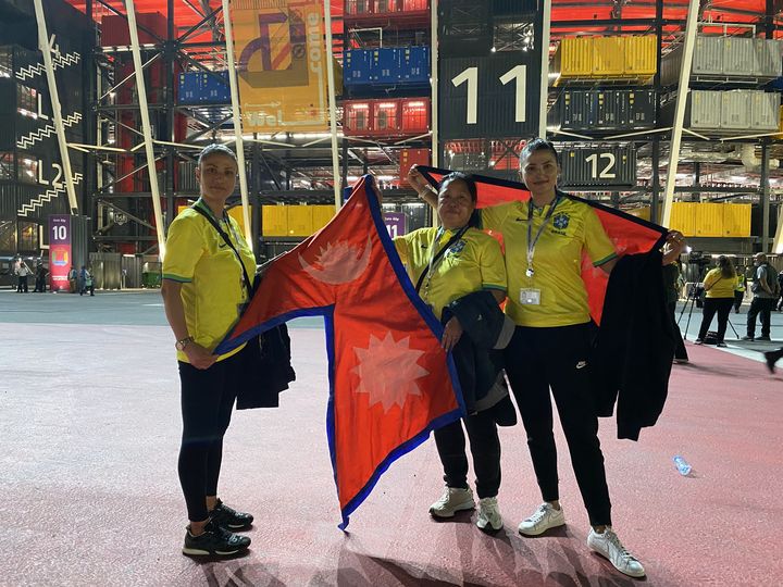 Sadina, Sarila et Bindra, originaires du Népal, posent avec leur drapeau devant le stade 974, le 28 novembre 2022, à l'occasion du match Brésil-Suisse à Doha (Qatar). (RAPHAEL GODET / FRANCEINFO)