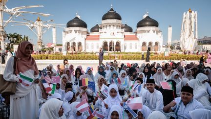 Des enfants brandissent des drapeaux nationaux lors des prières à la Grande Mosquée Baiturrahman, à Banda Aceh (Indonésie). (YASUYOSHI CHIBA / AFP)