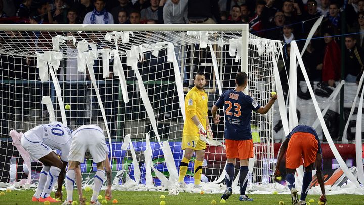 Les joueurs d'Auxerre et de Montpellier ramassent des balles de tennis jet&eacute;es par des supporters lors du match entre les deux &eacute;quipes, le 20 mai 2012, &agrave; Auxerre. (JEFF PACHOUD / AFP)