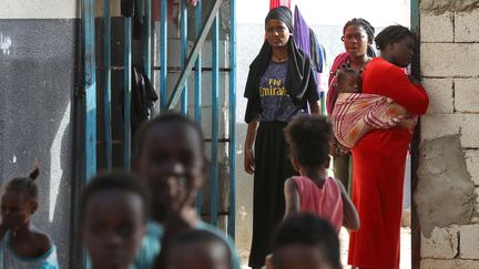 Des migrants africains regroupés dans un camp de fortune dans une banlieue de Tripoli, le 11 octobre 2021. (MAHMUD TURKIA / AFP)