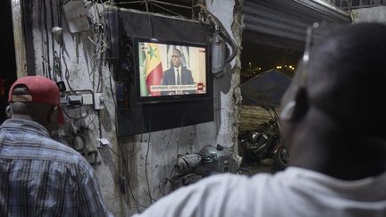 Des Sénégalais regardent l'intervention du président Macky Sall, le 22 février 2024, à Dakar. (MICHELE CATTANI / AFP)