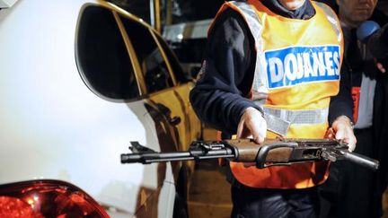 Un agent des douanes saisit une kalachnikov trouv&eacute;e dans le coffre d'une voiture, lors d'une op&eacute;ration de contr&ocirc;le, &agrave; Marseille, le 22 novembre 2010. (ANNE-CHRISTINE POUJOULAT / AFP)