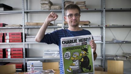 Le dessinateur Charb pose avec la une d'un numéro de "Charlie Hebdo", le 19 septembre 2012 dans les locaux du journal à Paris. (FRED DUFOUR / AFP)