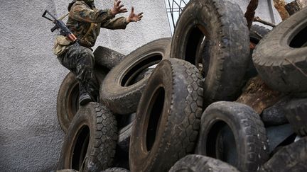 Un homme arm&eacute; gesticule sur une barricade construite devant le quartier g&eacute;n&eacute;ral de la police &agrave; Slaviansk (Ukraine), le 12 avril 2013. (GLEB GARANICH / REUTERS)