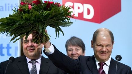 Le future maire SPD de Hambourg, Olaf Scholze (à droite), brandit les fleurs de la victoire. (AFP - JOHANNES EISELE)