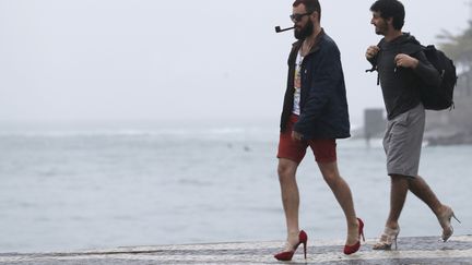 Deux hommes en talons aiguilles sur&nbsp;la plage de Copacabana, &agrave; Rio (Br&eacute;sil),&nbsp;protestent contre la venue du pape Fran&ccedil;ois &agrave; l'occasion des JMJ, le 24 juillet 2013. (SERGIO MORAES / REUTERS)