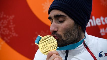 Le biathlète Martin Fourcade embrasse sa médaille d'or olympique décrochée sur la mass start à Pyeongchang (Corée du Sud), le 19 février 2018. (FRANCK FIFE / AFP)