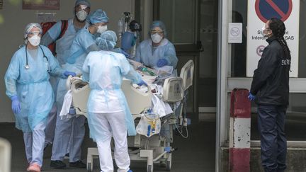 Des soignants transportent un malade du coronavirus, à l'hôpital de Mulhouse (Haut-Rhin), saturé en raison de l'épidémie. (SEBASTIEN BOZON / AFP)