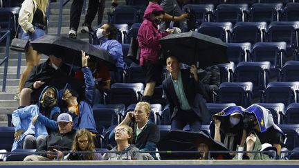 Scène incroyable sur le court central Arthur-Ashe de New York : les spectateurs contraints de sortir les parapluies pour s'abriter des intempéries causées par l'ouragan Ida, alors même que le toit du terrain était fermé, le 1er septembre 2021. (MAXPPP)