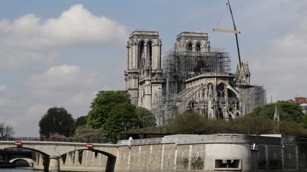 Une grue et des pompiers sur le site de la cathédrale Notre-Dame de Paris, après l'incendie qui l'a ravagée. (THOMAS SAMSON / AFP)