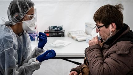 Une femme procède à un test salivaire, le 22 février 2021 à Saint-Etienne (Loire). (JEAN-PHILIPPE KSIAZEK / AFP)