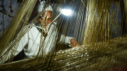 Un&nbsp;tisserand sur un métier à main pour confectionner un sari en soie dans un atelier de Varanasi (Inde),&nbsp;en&nbsp;novembre 2021. (MONEY SHARMA / AFP)