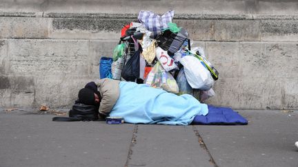 Un mendiant couché dans un sac de couchage dans la rue avec ses affaires à Paris. (NATHANAEL CHARBONNIER / FRANCE-INFO / RADIO FRANCE)