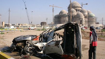 Un véhicule explosé à Mossoul, avec en fond une mosquée de la ville irakienne
 (MUJAHED MOHAMMED / AFP)