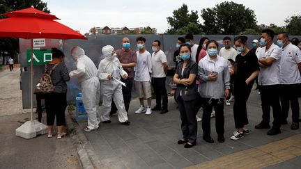 Des habitants de Pékin, masqués, font la queue pour être dépistés après une recrudescence de cas de coronavirus dans la capitale chinoise. (TINGSHU WANG / REUTERS)