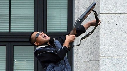 A Tokyo, le 5 juillet 2015, un homme prend part à des exercices anti-terroristes, en tenant un fusil sur un balcon de la Diète nationale, où est situé le Parlement. (TOSHIFUMI KITAMURA / AFP)