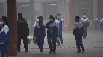 Des écoliers chinois avec des masques anti-pollution sortent de classe, à Tianjin, le 19 décembre. Mercredi 21 décembre, certaines villes du nord de la Chine, à l'image d'Hebei, ont pris la décision de fermer leurs écoles.&nbsp; (LI XIAOFEI / IMAGINECHINA)