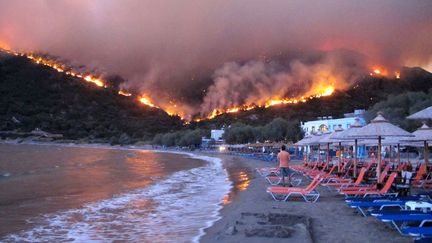 Des habitants du village de Lithi observent depuis la plage le feu qui se propage dans les montagnes de l'&icirc;le de Chios (Gr&egrave;ce), le 18 ao&ucirc;t 2012. (ALEXANDROS VLACHOS / EPA / MAXPPP)