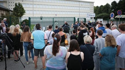 Elus, enseignants et élèves rassemblés le 15 août 2023 devant le collège Pierre-Simon De Laplace pour rendre hommage à son principal, retrouvé mort dans l'établissement. (LOU BENOIST / AFP)