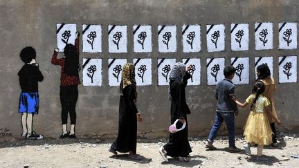 Des personnes regardent des inscriptions &agrave; la m&eacute;moire des victimes de frappes a&eacute;riennes, &agrave; Sanaa (Y&eacute;men), le 18 mai 2015. (MOHAMMED HAMOUD / ANADOLU AGENCY / AFP)