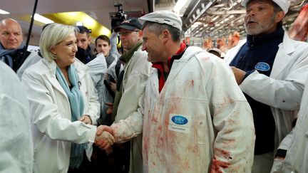 La candidate du Front national à l'élection présidentielle Marine Le Pen serre les mains d'un boucher en visitant le pavillon de la viande, au marché de Rungis (Val-de-Marne), le 25 avril 2017. (CHARLES PLATIAU / POOL)