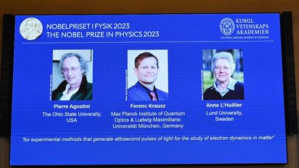 Un écran montre les trois lauréats du prix Nobel de physique, le 3 octobre 2023, lors de la cérémonie à Stockholm (Suède). (JONATHAN NACKSTRAND / AFP)