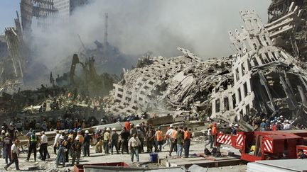 Les secouristes poursuivent leurs recherches alors que de la fumée s'élève des décombres du World Trade Center, le 13 septembre 2001 à New York.  (BETH A. KEISER / AP POOL)