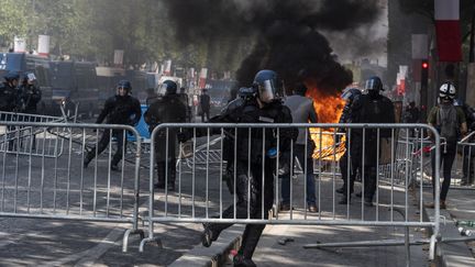 Les forces de l'ordre sur l'avenue des Champs-Elysées à Paris, dimanche 14 juillet, lors des affrontements avec des manifestants peu après le défilé militaire. (SAMUEL BOIVIN / NURPHOTO / AFP)