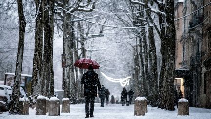 Un homme marche dans une rue enneigée de Lyon, le 18 décembre 2017. (JEFF PACHOUD / AFP)