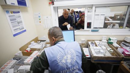 An employee of the UN agency for Palestinian refugees distributes medicine, in Gaza, January 21, 2024. (ASHRAF AMRA / ANADOLU / AFP)