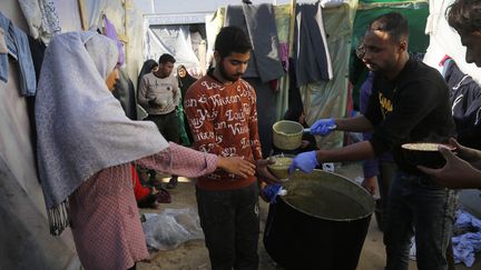 Des déplacés palestiniens lors d'une distribution alimentaire à Deir Al-Balah, dans la bande de Gaza, le 16 décembre 2023. (ASHRAF AMRA / ANADOLU / AFP)