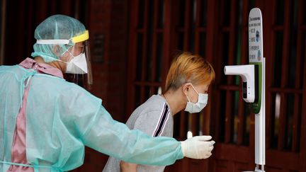 Une Taïwannaise se fait prendre sa température avant d'effectuer un dépistage au coronavirus à Taipei, le 15 mai 2021 (RITCHIE B. TONGO / EPA)