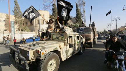 Des jihadistes de l'Etat islamique paradent dans la ville de Raqqa, peu après la prise de la ville, le 30 juin 2014. (STRINGER / REUTERS)