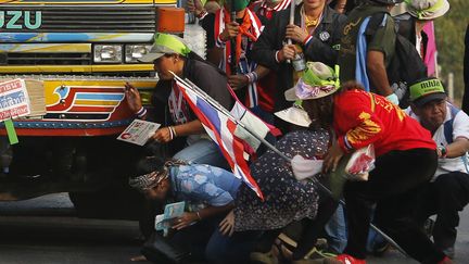 Des manifestants se mettent &agrave; l'abri derri&egrave;re un bus pendant des &eacute;changes de coups de feu entre manifestants et forces de police &agrave; Bangkok (Tha&iuml;lande), le 1er f&eacute;vrier 2014. (DAMIR SAGOLJ / REUTERS)