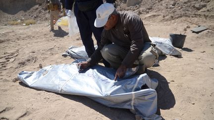 Un m&eacute;decin l&eacute;giste &eacute;crit sur un sac contenant un corps exhum&eacute; d'une fosse commune de la ville de Tikrit (Irak), le 6 avril 2015. (REUTERS)