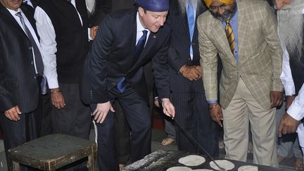 Le Premier ministre britannique David Cameron (C) pr&eacute;pare le pain dans la cuisine du Temple d'Or &agrave; Amritsar (Inde), le 20 f&eacute;vrier 2013. (MUNISH SHARMA / REUTERS)