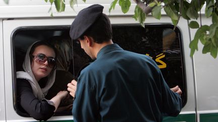 Un policier iranien parle à une femme arrêtée pour une tenue "inappropriée" à Téhéran, le 23 juillet 2007. (BEHROUZ MEHRI / AFP)