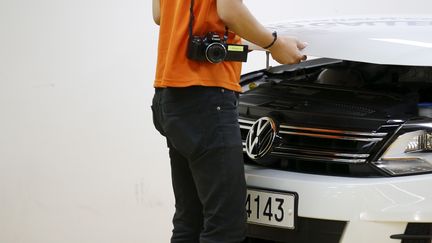 Un homme soul&egrave;ve le capot d'une Volkswagen, le 2 octobre 2015, &agrave; S&eacute;oul (Cor&eacute;e du Sud). (KIM HONG-JI / REUTERS)