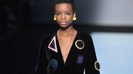 Palette sombre chez Emporio Armani dans un registre classique : le tailleur en vinyle noir, les confortables pantalons à pinces, les shorts bouffants et les manteaux sinueux. L'ensemble est égayé par des figures géométriques. Triangles, ronds et carrés jaune, rose, bleu et vert sont omniprésents dans les accessoires - bijoux et sacs - et sur les vêtements. Ils sont déclinés en micro motifs sur tops et blouses, jouent les smileys  sur des pulls, se multiplient en format géant sur des tops ou le bas d'un manteau. Ailleurs, disséminés et fluorescents, ils illuminent une robe noire ou sont appliqués comme dans un tableau abstrait sur des tops transparents.
 (TIZIANA FABI / AFP)