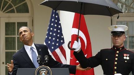 Le président des Etats-Unis, Barack Obama, vérifie s'il va pouvoir se passer d'un parapluie pendant une conférence de presse à la Maison blanche le 16-5-2013.  (Reuters - Jason Reed)