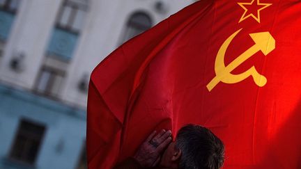 Un homme embrasse un drapeau soviétique square Lénine à Simféropol (Crimée), le 16 mars 2014. (FILIPPO MONTEFORTE / AFP)