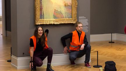 Des militants pro-climat, mains collées au mur, après avoir lancé de la purée sur "Les Meules", tableau de Claude Monet,&nbsp;le 23 octobre 2022 au musée Barberini de Potsdam. (HANDOUT / LAST GENERATION VIA AFP)