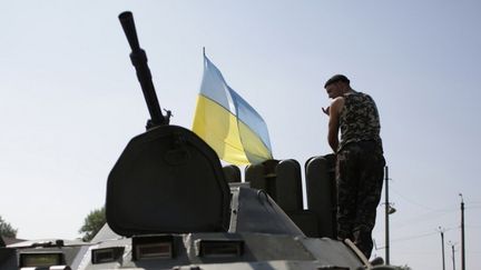 Un soldat ukrainien en poste sur un blind&eacute; flanqu&eacute; d'un drapeau ukrainien, le 16 ao&ucirc;t 2014 dans la r&eacute;gion de Donetsk (Ukraine). (ANATOLII STEPANOV / AFP)